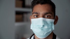 Mixed race male doctor standing in doctors office wearing surgical mask