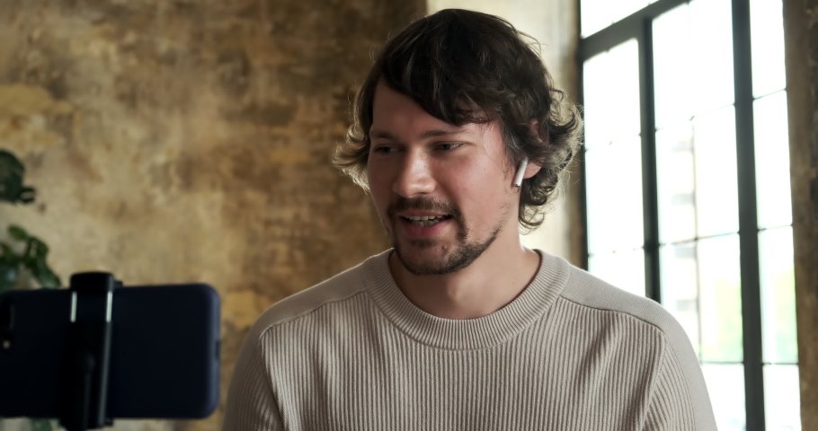 Male blogger streaming online in a social network and communicates with his subscribers, recording an educational video, chatting a video call with friends using his phone, shooting vlog.