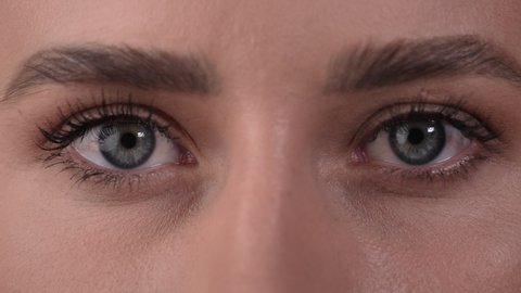 Close up of a Caucasian woman's eyes, closing for a while and opening her eyes. White background.