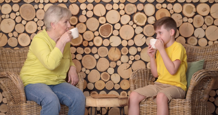 Little boy and his grandmother drinking tea at home