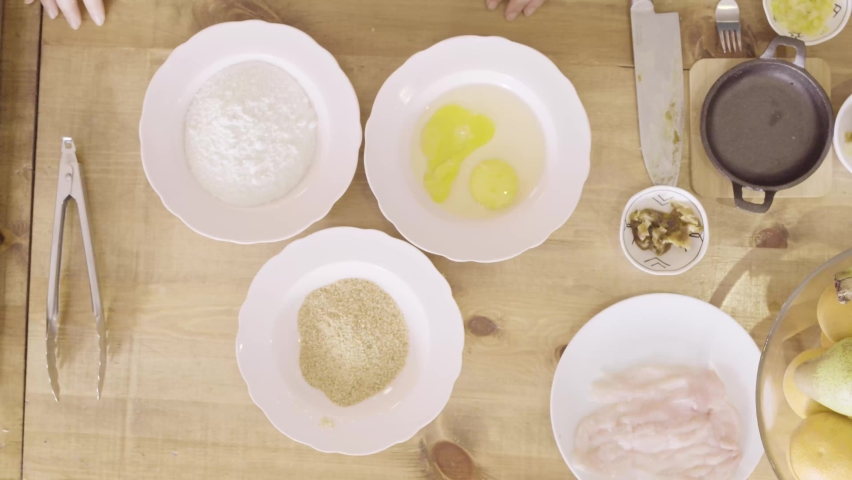 Cook sprinkling salt on eggs then stirring them up on a white plate, top view static
