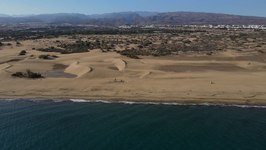 Aerial drone view, flying from the ocean to the beach. Amazing aerial view of a beach on the Gran Canaria island Maspalomas in Spain. Shot in 4K. | Shutterstock HD Video #1077859643