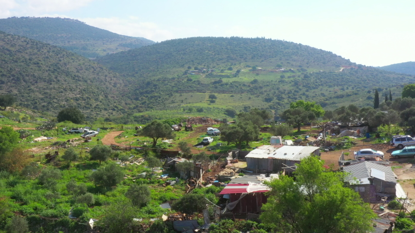 Aerial Forward Descending Shot Of Cars Over Green Mountains In Village On Sunny Day - North District, Israel