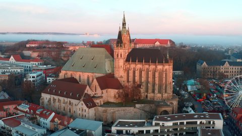 Aerial Panning Shot Of St. Severus Church In Old Town, Drone Flying Over Ferris Wheel During Sunrise - Erfurt, Germany