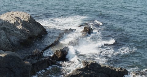 Sea waves crashing into rocks in slow motion