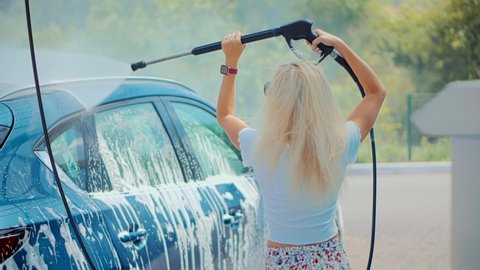 Woman Washing Car On Wash Self-Service.Washes Automobile Active Foam And Osmosis Water.Car Wash And Waxing Vehicle.Dirty Car Cleaning And Protection With Active Foam.Clean Water Spray Pressure.