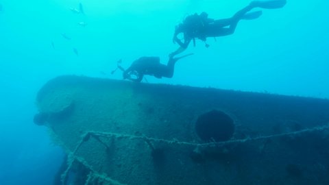 Group of scuba divers swims on the shipwreck Swedish ferry MS Zenobia. Slow motion, Wreck diving. Mediterranean sea, Cyprus