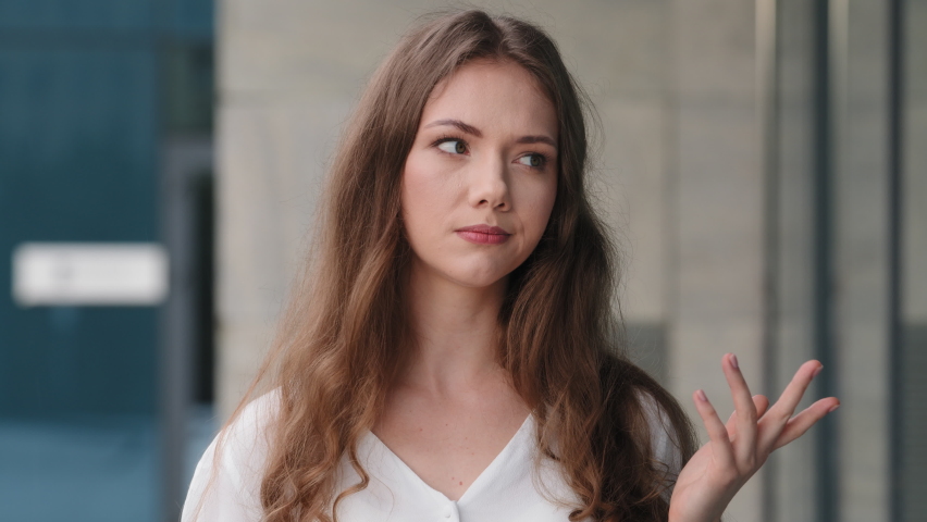 Female portrait outdoors caucasian millennial girl pensive puzzled woman make choice thinking chooses thinks over idea making gesture with hands weighing like scales shrugs in exactly unknown not sure Royalty-Free Stock Footage #1077869789