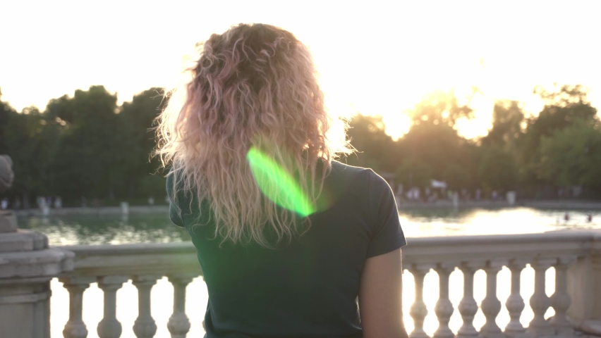 woman smiles at sunset at park lake 