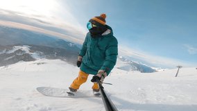 Man riding on snowboard with selfie stick in his hand downhill kamchatka mountain. Guy filming selfie during riding down. Concept of extreme, sport, winter, freeride, snowboarding