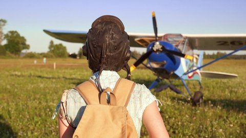 Woman pilot portrait walking to her small airplane at summer sunny weather. Active female flier doing sport. Aircraft and technology concept. Retro vintage style.
