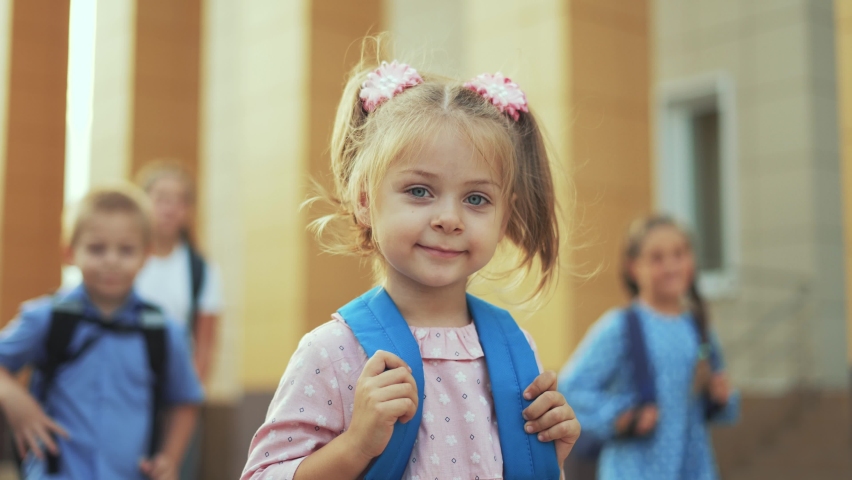 Happy girl back to school. Child goes to school with backpack. Girl with backpack walk through schoolyard. Happy family concept. Back to school. Girl walk to school with blue backpack in schoolyard Royalty-Free Stock Footage #1077874316