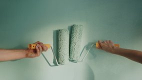 Closeup man hand holding paint roller on wall. Unknown woman hand leading roller to another one on surface. Unrecognizable couple painting new apartment together. - Powered by Shutterstock - Get 15% off with code: PIKWIZARD15