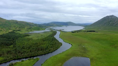 Bealanabrack River, Maum, Connemara, County Galway, Ireland, July 2021. Drone gradually follows the course of the river while pushing east over forrest and grassy marshland towards Lough Corrib.