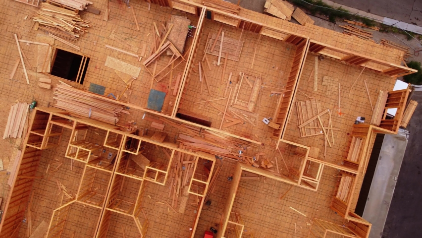 Wood framed construction site left abandoned as work stopped due to pandemic supply chain shutdown. Drone looking straight down over 4 story building to show sidewalk and road.  Royalty-Free Stock Footage #1077882986