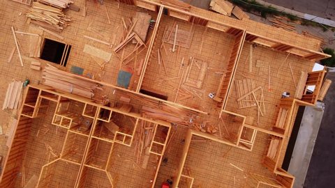 Wood framed construction site left abandoned as work stopped due to pandemic supply chain shutdown. Drone looking straight down over 4 story building to show sidewalk and road. 