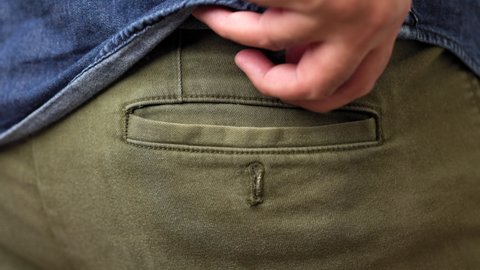 A young man takes a condom from the back pocket of his pants and is ready to use. Campaign for safe sex and contraception.