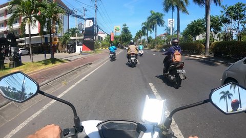 Bali, Cuta - Indonesia - 17 May 2021: First-person view from motorbike, People driving along a street Bali maneuvering in traffic. 4K