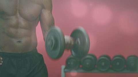 Spots of light against mid section of african american fit man working out with dumbbells at the gym. sports and fitness technology concept