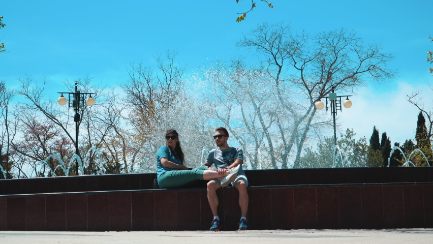 A guy and a girl sitting on a fountain