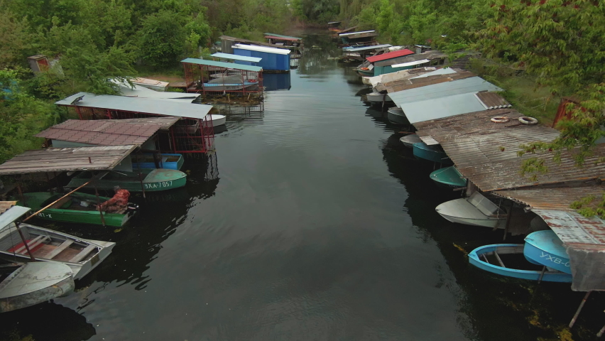 Drone flight over small rural river landscape with boat parking space. Many colorful motorboats in parking lot. Countryside. Summer scene.