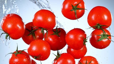 Super Slow Motion Shot of Flying Fresh Tomatoes and Water Side Splash at 1000 fps.