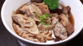 footage of a dish of Chinese wonton soup rotating close up spinning food
