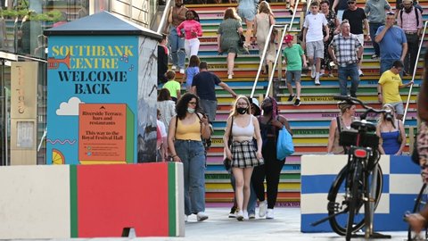 London, UK - July 1, 2021: crowds of people, some wearing face masks, walk up and down colourful stairs at London Southbank Centre