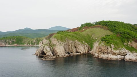 Drone view of the rocks and grottoes of Cape Kuzmin in the Gulf of Vladimir during the day. The sky is clouded over. Primorsky Territory, Russia
