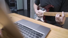 50Fps, a rock musician practicing his electronic guitar skill via an online free chords on internet, using digital laptop, social media entertaining online posing, live streaming, hard skill improving