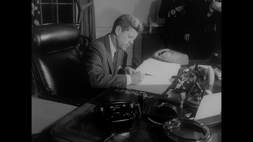 1960s: Titles. Front of White House. White House. President John F. Kennedy signs document at desk. Signature on document. Aerial photo of Cuban missile base.