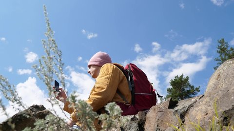 Forest tourist photographer man in the forest. Traveler videographer standing in nature with a tourist backpack captures landscapes and natural conditions using a smartphone camera