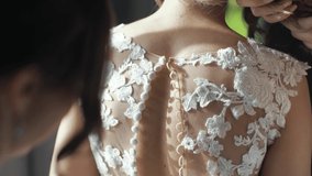 Close-up of the bridesmaid's hand buttoning the wedding dress. Morning preparation of the bride with white gown. Side closeup slow motion shot. - Powered by Shutterstock - Get 15% off with code: PIKWIZARD15