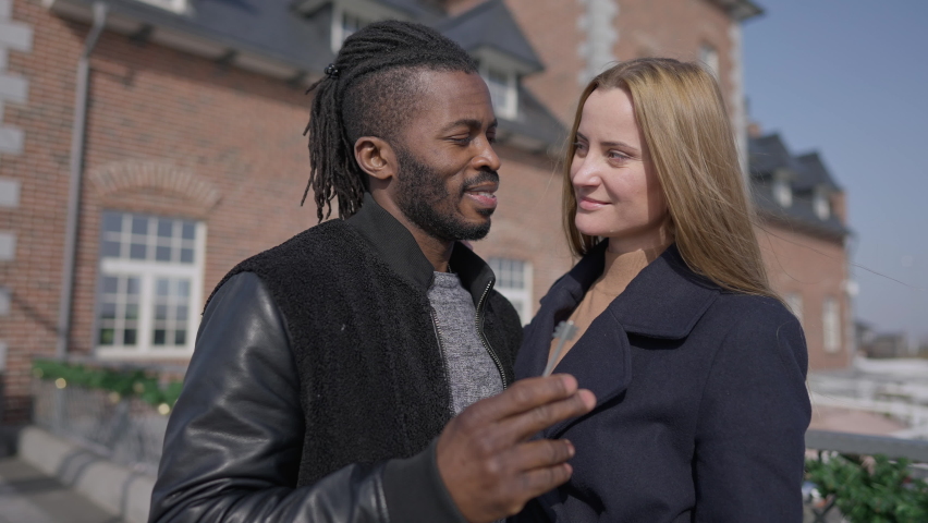 Happy successful interracial couple holding key from old-fashioned building looking at camera smiling. Rich African American man and Caucasian woman posing at private property outdoors in sunlight