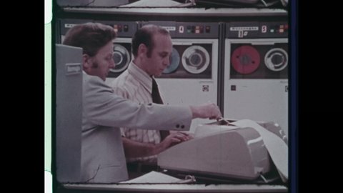 1970s Pasadena, CA. Two men operate a Burroughs Computer. The Burroughs Corporation B7500 Computer mainframe computer used primarily in banking industry. 4K Overscan of Vintage Archival 16mm Film 
