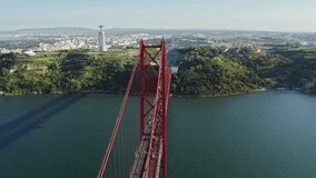 Ponte 25 de Abril, Lisbon, Portugal, Europe. Cinematic hillsides overlooking the Rio Tejo. Aerial footage of famous suspension bridge with Cristo Rei in the background. High quality 4k footage