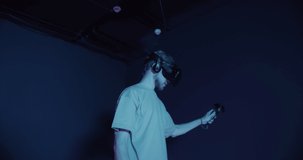 A man in virtual reality glasses, with joysticks in their hands, play 5D in a modern virtual reality center