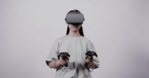 A girl of Asian appearance in virtual reality glasses with joysticks in her hands plays in a 5D attraction. A new generation of virtual games