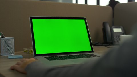 Business man using green screen laptop computer in office. Green screen computer closeup. Unrecognizable man working on laptop chroma key. Closeup of computer greenscreen