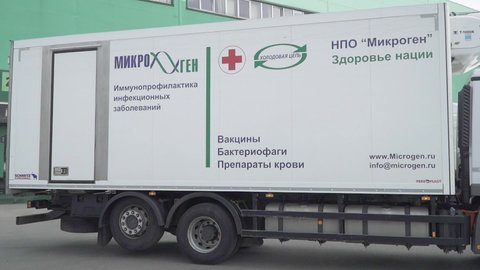 MOSCOW, RUSSIA - February 14, 2021: Transporting Kovivac vaccine by refrigerated trucks. Crates with packages of Kovivac vaccine and an employee of the logistics company at the Kovivak storage