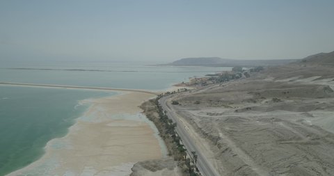 Aerial view of vehicles driving a scenic road along the Dead Sea shoreline in Jordan Rift Valley, Negev, Israel.