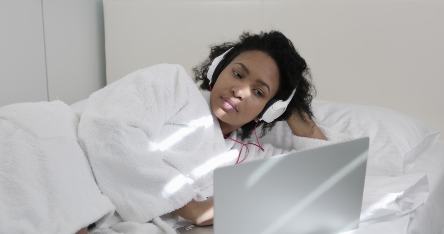 African American woman with headphones communicates online on a laptop. Online chat virtual screen. 