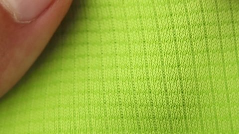 green sports breathable synthetic fabric, vapor permeable textile for running and fitness, hand makes stretching test, close-up macro view