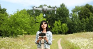 Young woman learning how to pilot her drone in, female using, piloting, fly drone on field of flowers, summer, agriculture.