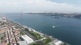 Ponte 25 de Abril, Lisbon, Portugal, Europe. Coastal town with one of the World's longest suspension bridges. Aerial footage of wide river between suburbs. High quality 4k footage