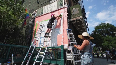 
NEW YORK, USA – JULY 2: Artists create mural on the building wall at front of Subway entrance in East Village at New York City NY USA on July 02 2020. Art by Sara Erenthal.
