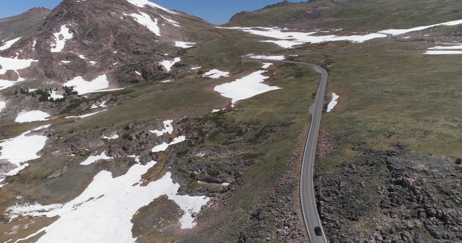 Car and motorbikes going up on curvy mountain road. Aerial view of Beartooth Highway in early summer, Wyoming