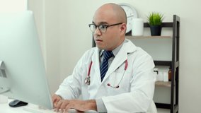 Young asian doctor working online texting on the keyboard video conference with team. Close Up Physician in white coat, stethoscope working with computer