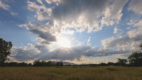 heavenly clouds blue sky. sunbeams rays shines through the gray clouds. vivid color of the sky in summer morning, evening sunset time. panoramic aerial view sunlight shines on yellow rice field. 