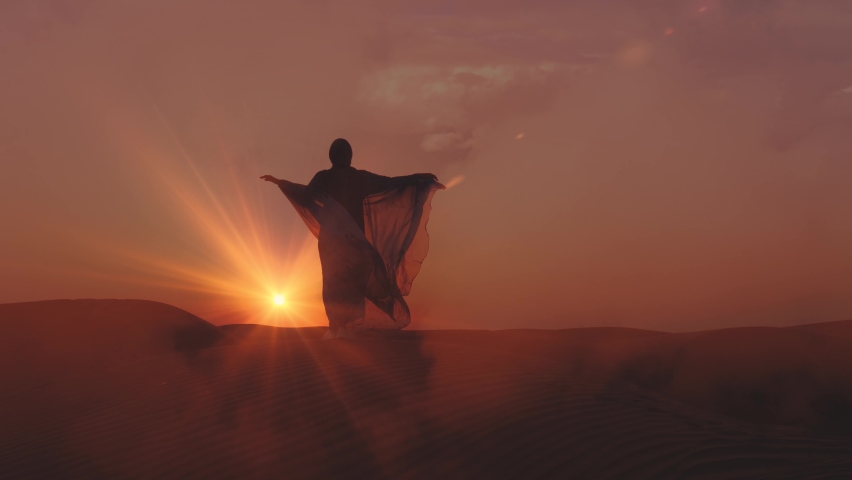 Young woman in traditional Abaya dress and in hijab enjoys nature in the desert at sunset. Woman rising her hands stand at the peak of deserts mountains with fog and wind | Shutterstock HD Video #1077976853